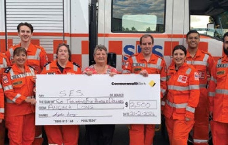 Angela long standing with SES volunteers holding a giant cheque