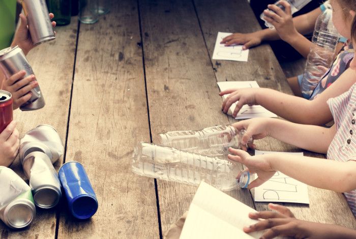 Children hands with plastic bottles and cans on wooden table