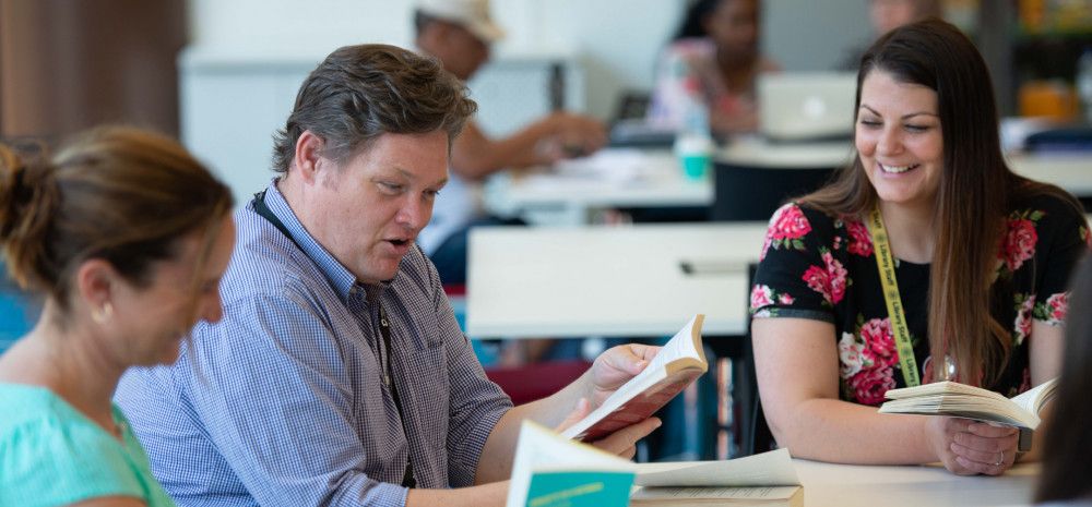 Three people sitting and reading together