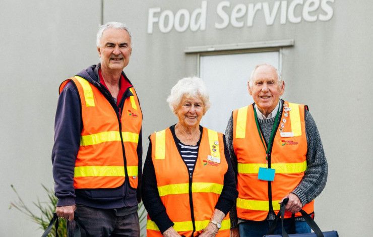 Three Meals on Wheels volunteers dressed in high-vis vests