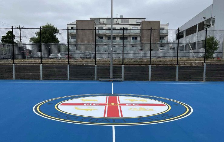 Bright blue court surface in an urban setting surrounded by high rise buildings