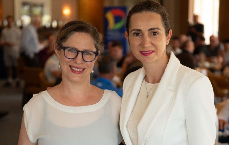 Two women dressed in white standing close together.