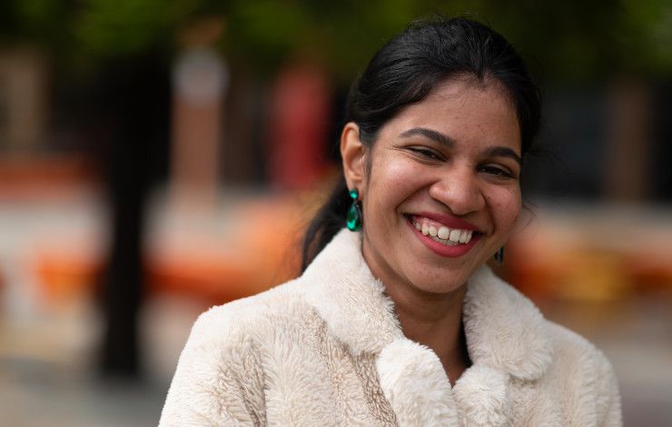 Young woman in a fluffy white coat smiling at the camera.