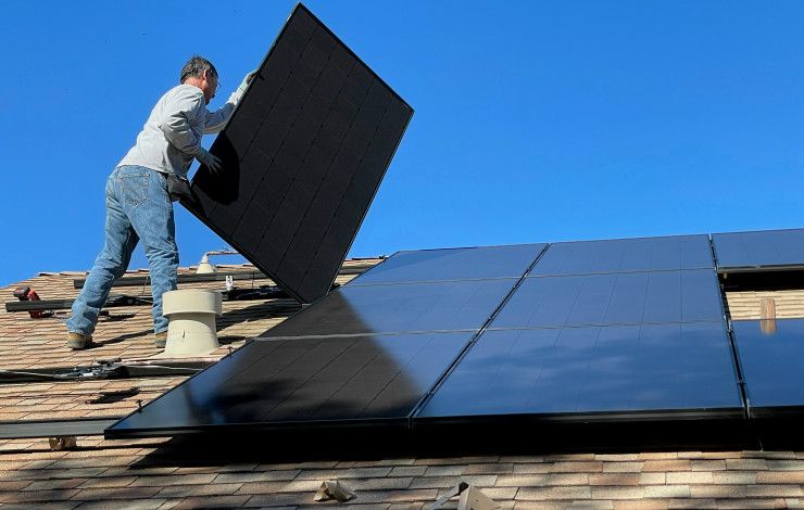 A man installing solar panels on the roof of a house