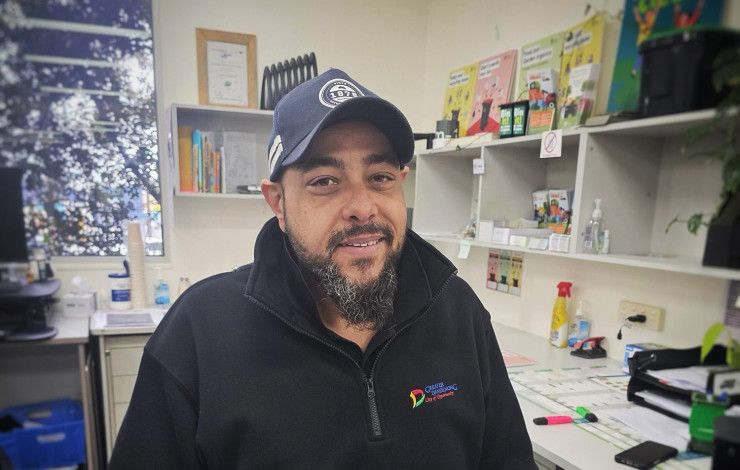 A smiling man in a cap and a dark jumper.