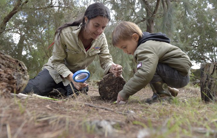 A woman and a young boy crouch down and are playing on the ground together