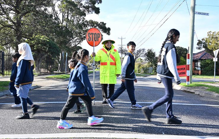 A man with a stop sign and children using a crossing