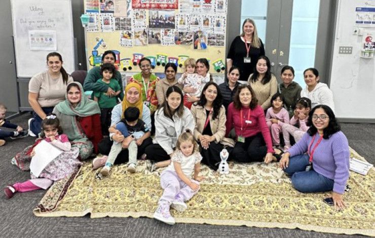 A large group of mums and their children smiling at the camera