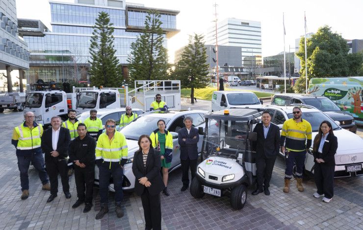 A small crowd of people standing next to a range of electric vehicles
