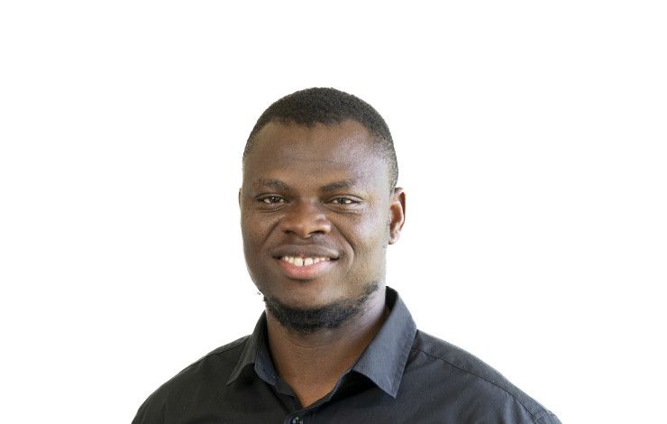 A smiling man dressed in a black shirt against a plain white background.