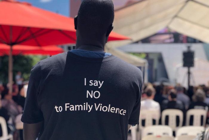 man with back to us with 'I say no to family violence' t-shirt on