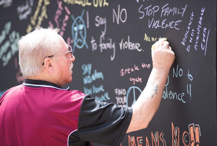 man writing on chalk board leaving message on white ribbon day