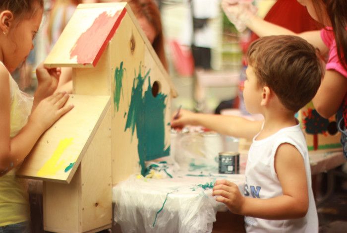 Young boy painting a wooden house