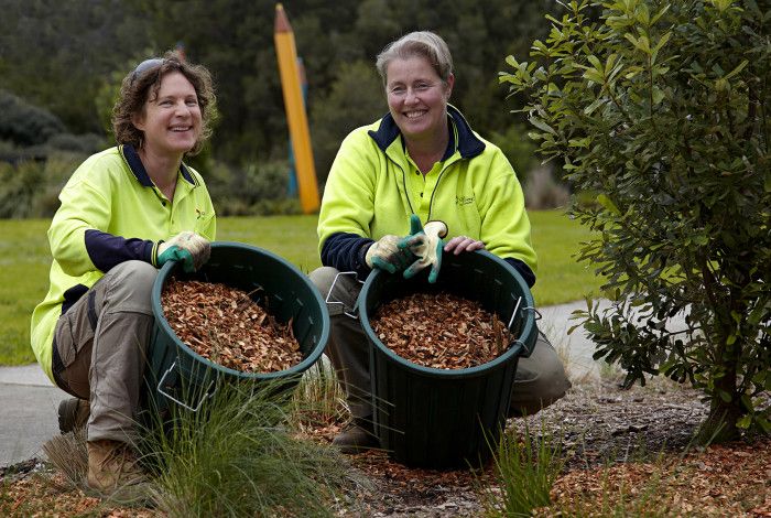 Two Parks team members adding mulch to a garden