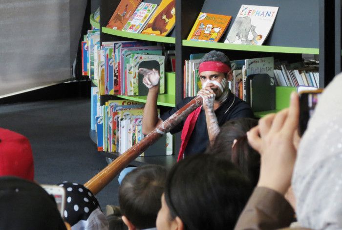 Photo of a man playing a didgeridoo in the library
