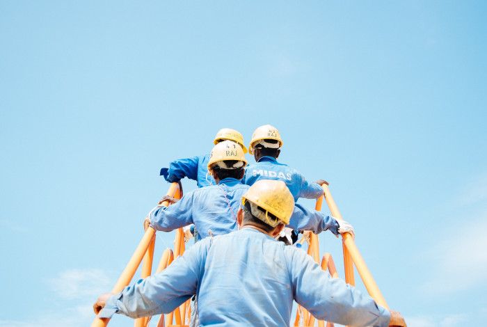 workers in hard hats climbing a ladder