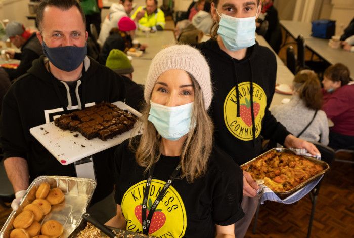 Volunteers from Kindness Community holding plates of food