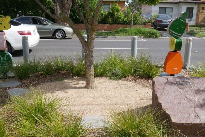 Sculptures and a garden with a plaque on a rock.