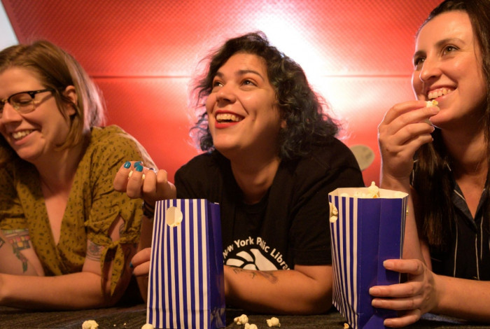 Image: Three women eating popcorn and watching a film