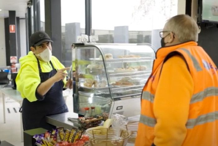 a person serving another person at a cafe counter 