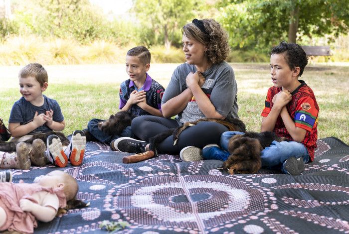 a group of people sitting on a rug outside 