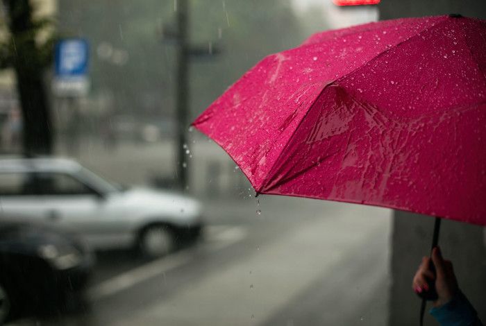 A red umbrella getting rained on.