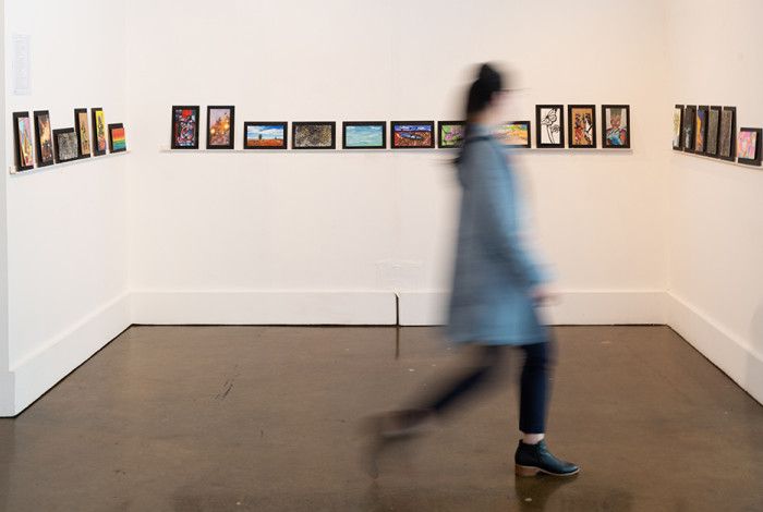 Person walking past artworks on gallery wall