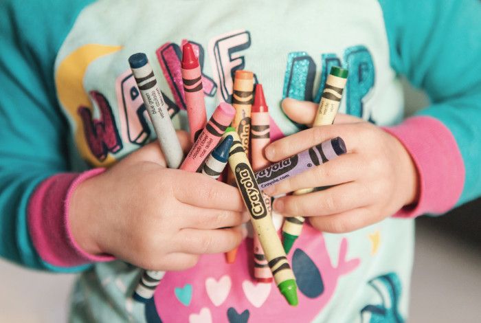 A child holding lots of colourful crayons