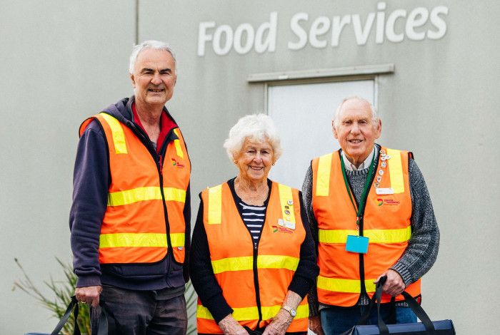 Three Meals on Wheels volunteers dressed in hi-vis vests