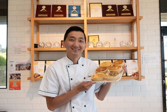 Man holding a tray of pies at his business