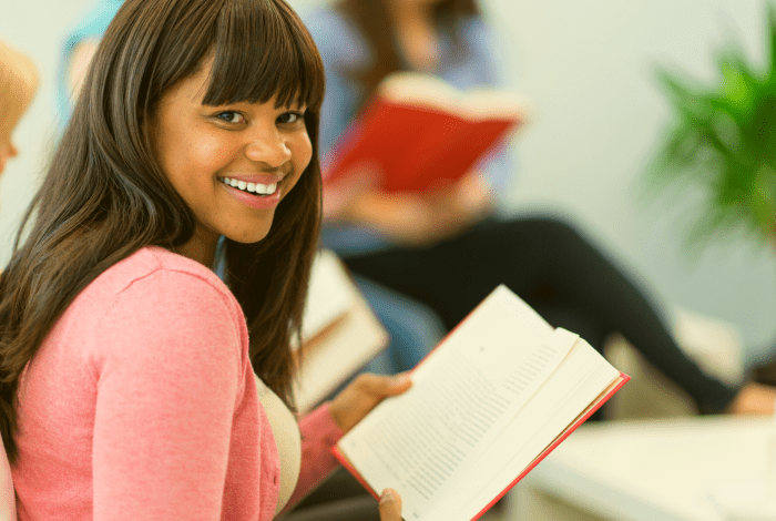 A person reading a book and smiling at the camera