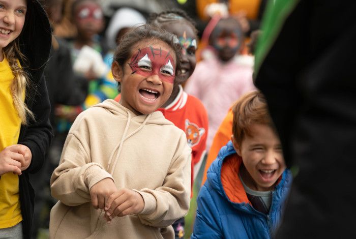 A laughing child with face painted like spiderman