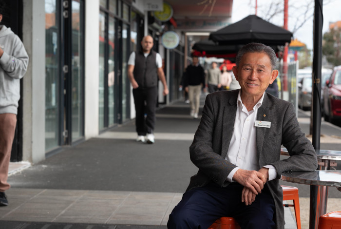 Councillor Richard Lim sitting on street furniture in Springvale