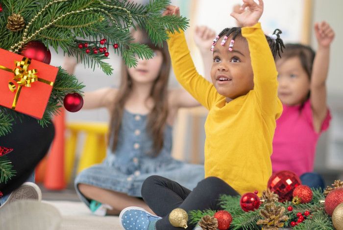 A group of children enjoying stories at the library. There are christmas presents and a christmas tree.