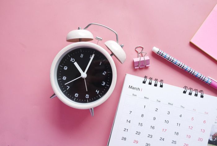 pink desk with alarm clock and calendar