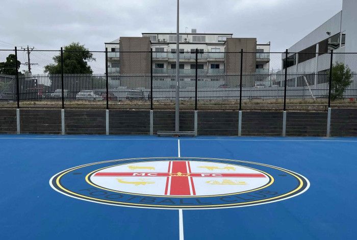 Bright blue court surface in an urban setting surrounded by high rise buildings