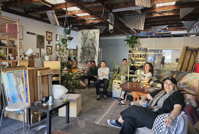 Five people sitting on different chairs inside an art studio.