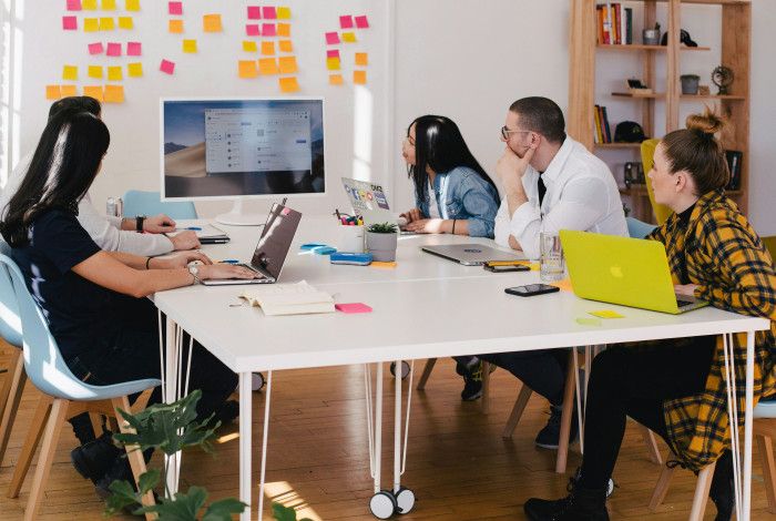 people meeting over a desk with a screen