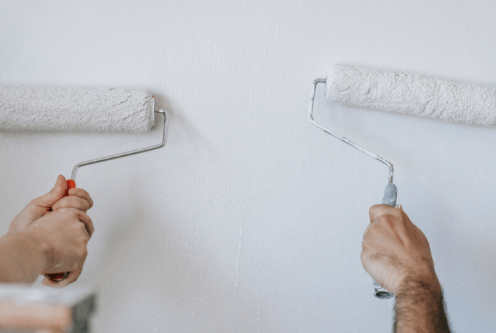 hands with rollers painting wall