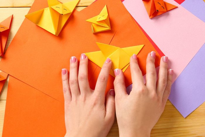 A woman's hands holding colourful origami papers.