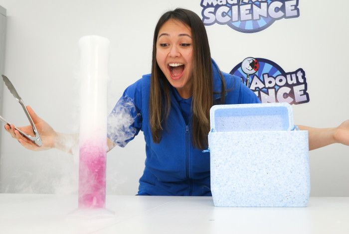 A young person wearing a blue jacket is conducting a science experiment.