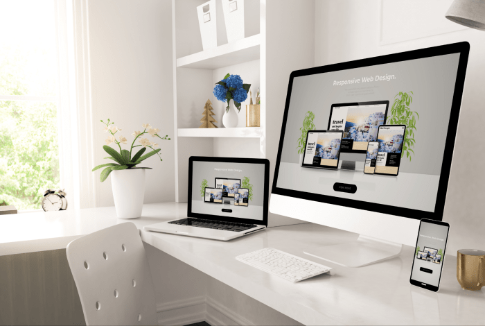 Two computers on a desk showing a website.