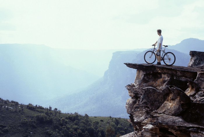 A person and a bicycle on a mountain.
