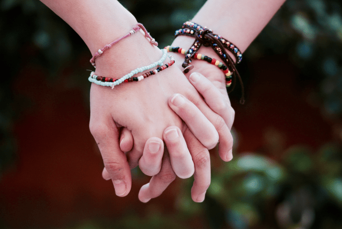 Holding hands wearing colourful friendship bracelets.
