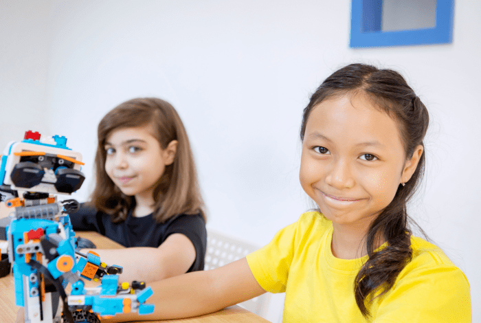 Two girls holding LEGO robots.