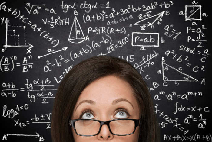 Woman standing in front of a blackboard with maths equations.