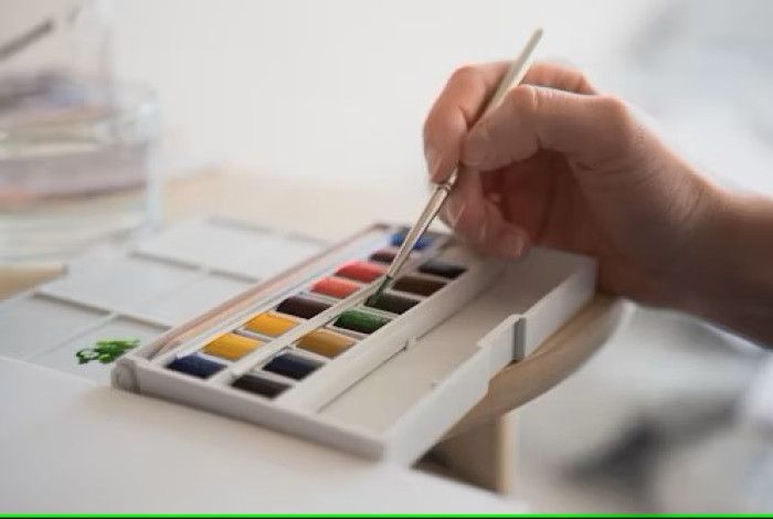 Person dipping brush into paint