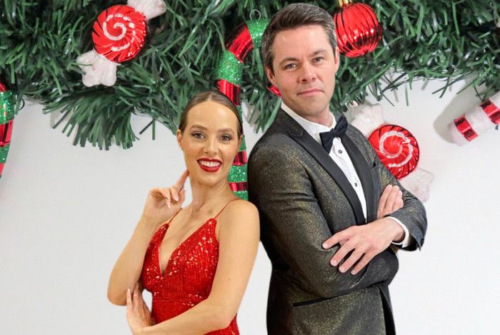 A women and a man standing in front of Christmas decorations