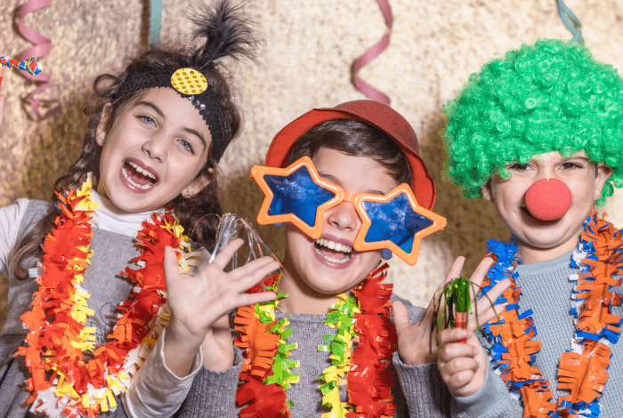 Three children dressed up in colourful costumes. They are smiling.