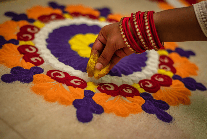 A hand holding coloured powder to create rangoli.